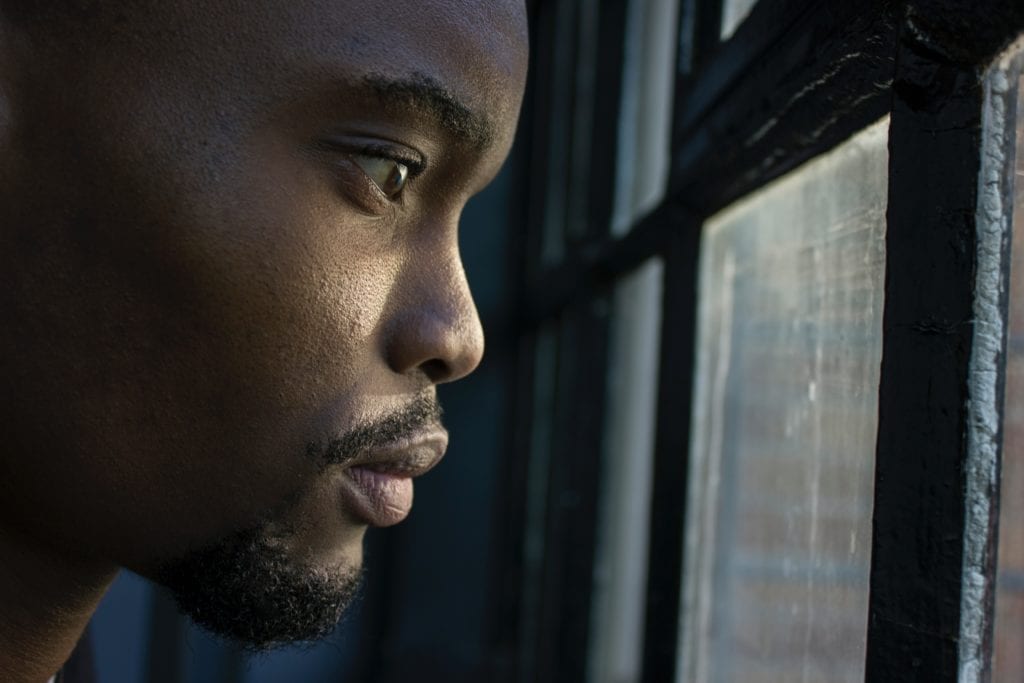 Man looking out of window looking anxious